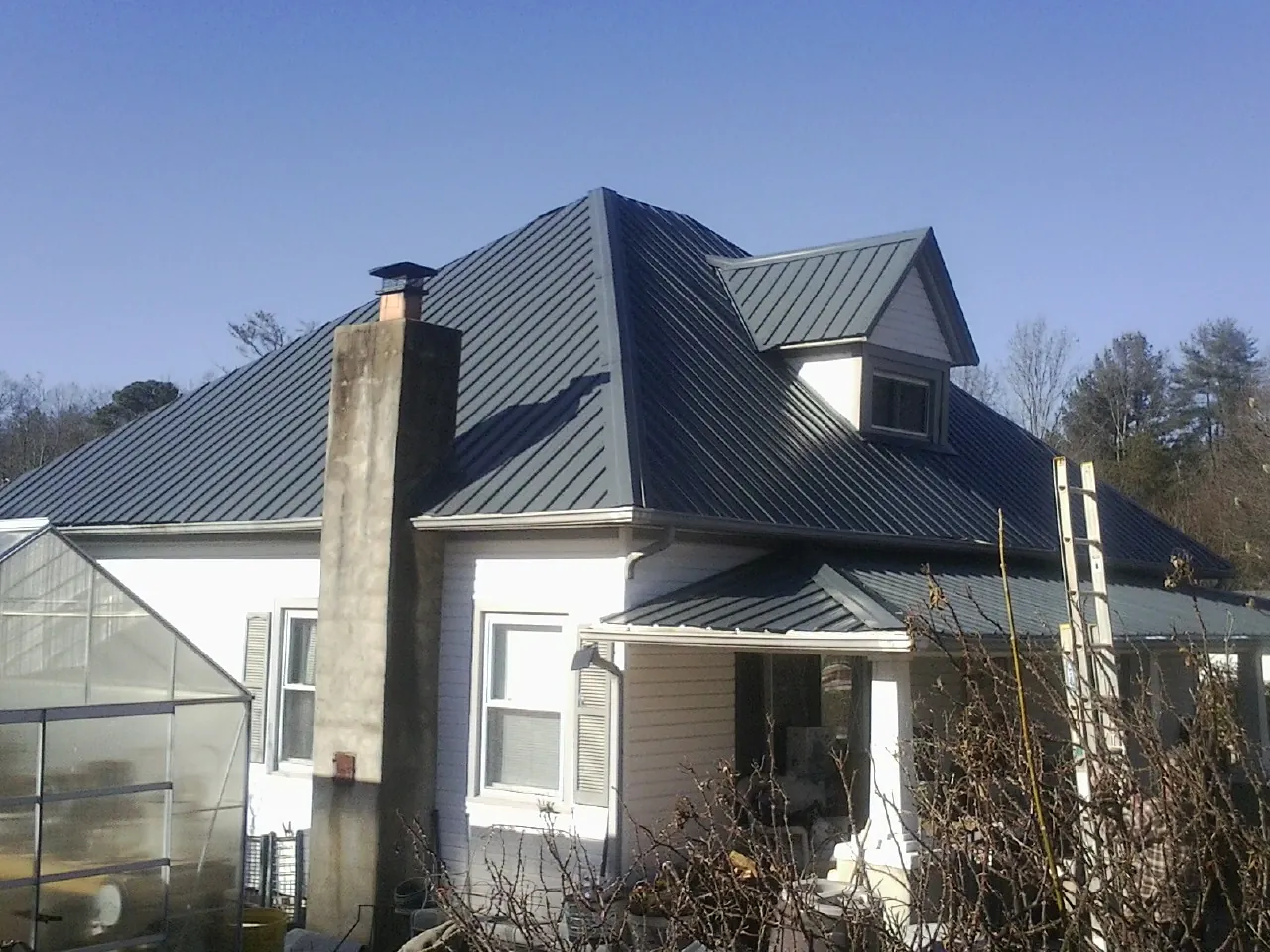 Dark blue standing seam metal roof on a white farmhouse with dormer — Slate & Tile Roof Repair by Roofing Brothers in Amlin