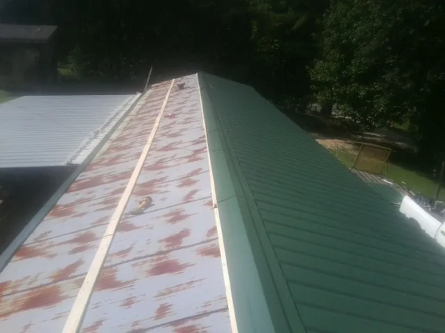 Old rusted panels beside newly installed green metal roofing — Wind Damage Roof Repair by Roofing Brothers in Amlin