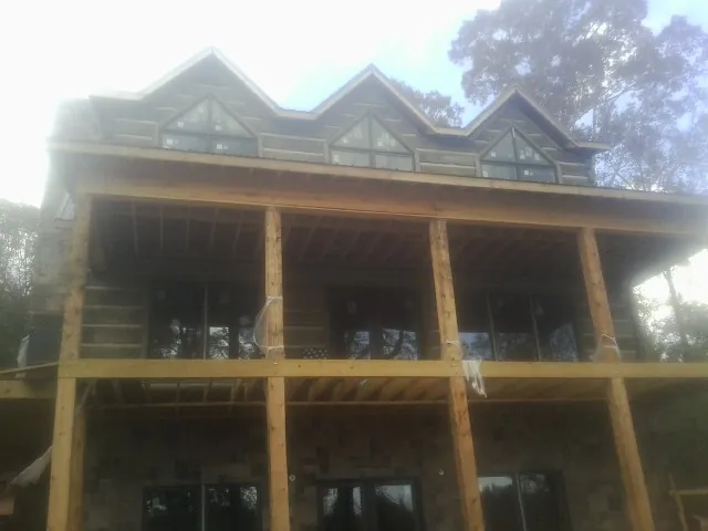 Dormers and porch framing on a large log home under construction — Roof Coating work by our crew in Amlin