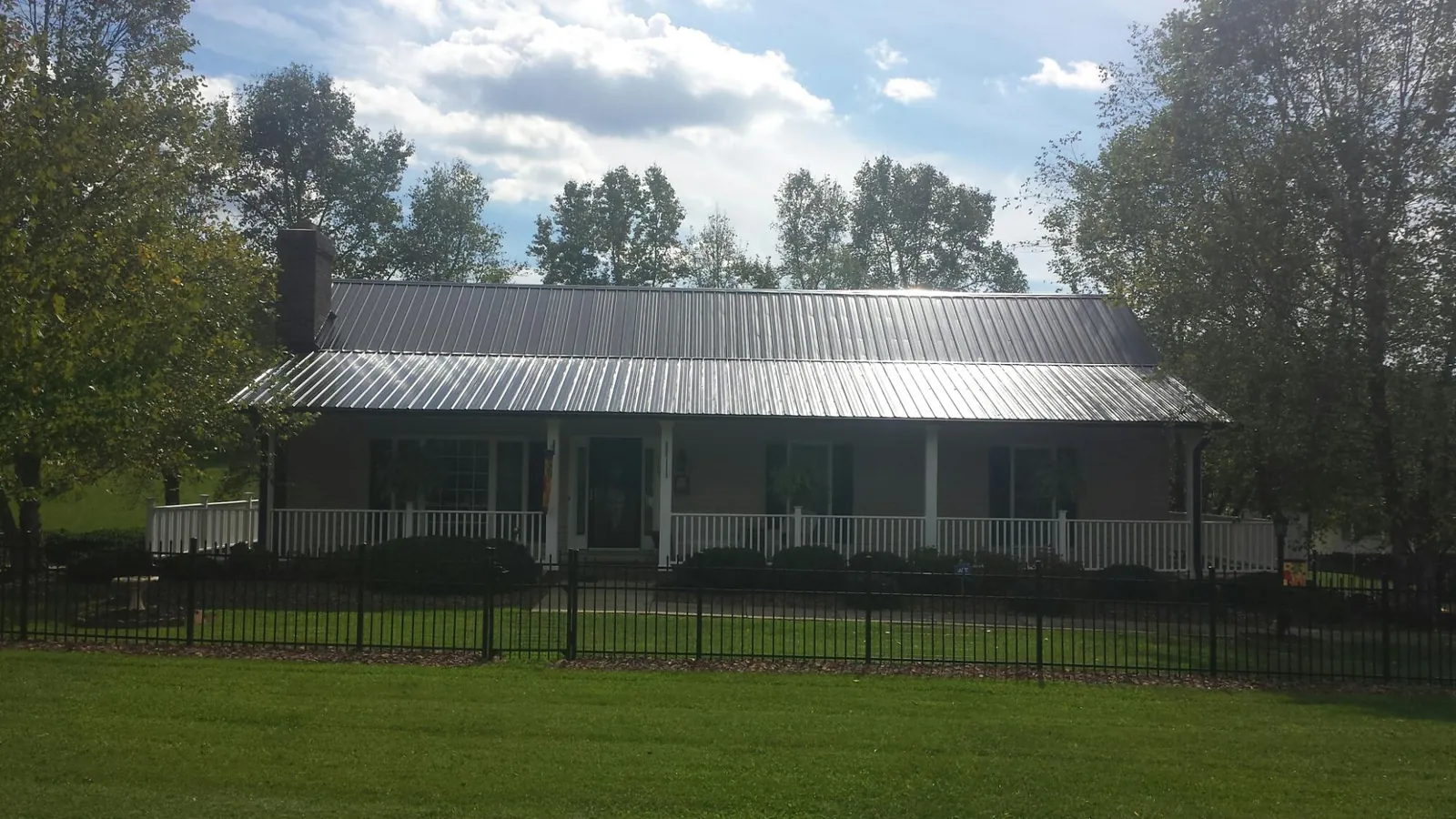 Gray metal roof on a brick ranch with a full width front porch — Gutter Guard Installation work by our crew in Amlin
