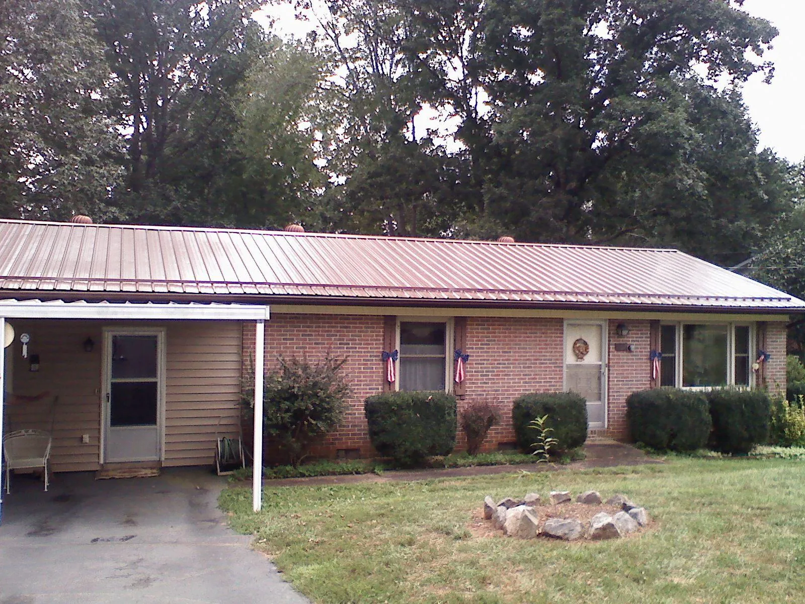 Bronze metal roof and carport on a brick ranch home — Roof Repair work by our crew in Amlin