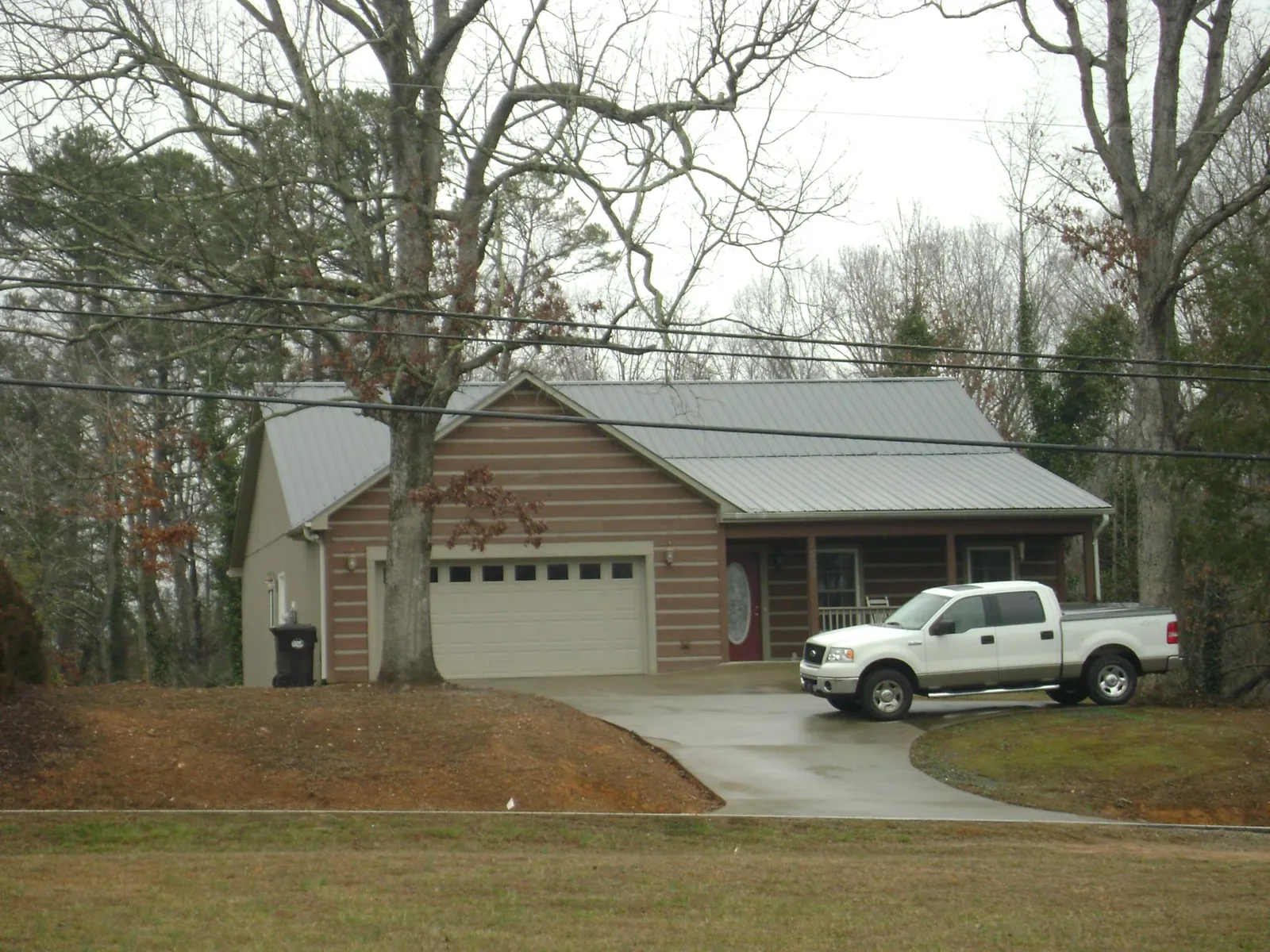 Gray metal roof on a log sided house with an attached two car garage in Amlin